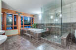 This luxurious bathroom boasts a spacious walk-in shower with glass enclosure and built-in seating, complemented by a modern freestanding bathtub set on a raised platform.