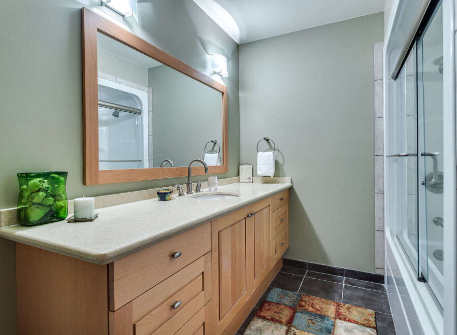 This charming bathroom boasts a light and airy feel, featuring a spacious vanity with ample storage, a large mirror, and a walk-in shower with glass doors.