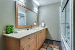 This charming bathroom boasts a light and airy feel, featuring a spacious vanity with ample storage, a large mirror, and a walk-in shower with glass doors.