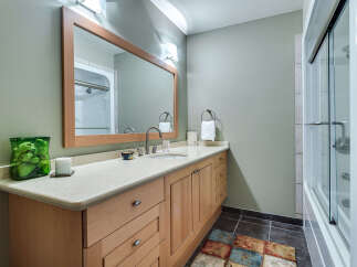 This charming bathroom boasts a light and airy feel, featuring a spacious vanity with ample storage, a large mirror, and a walk-in shower with glass doors.