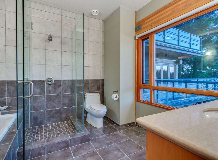 This luxurious bathroom boasts a spacious walk-in shower with glass enclosure and modern fixtures, complemented by dark brown and light beige tiles.