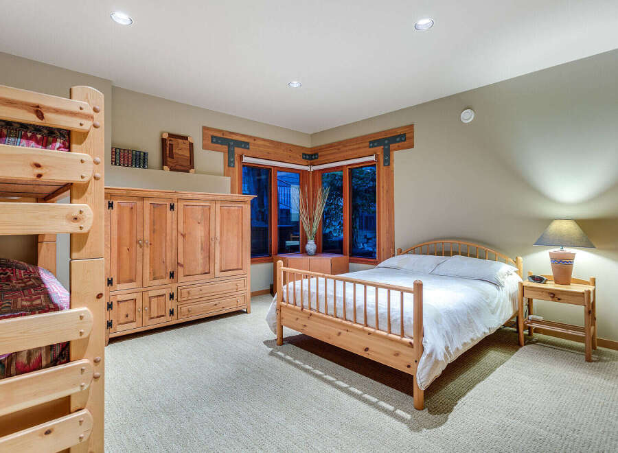 This charming bedroom boasts a rustic-chic aesthetic with a wooden double bed, a matching wooden wardrobe, and a built-in bunk bed, perfect for families.
