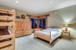 This charming bedroom boasts a rustic-chic aesthetic with a wooden double bed, a matching wooden wardrobe, and a built-in bunk bed, perfect for families.