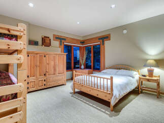 This charming bedroom boasts a rustic-chic aesthetic with a wooden double bed, a matching wooden wardrobe, and a built-in bunk bed, perfect for families.
