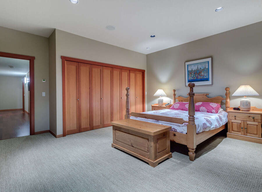 This charming bedroom boasts a cozy carpet, complemented by a wooden four-poster bed and matching nightstands.