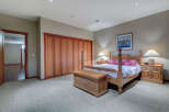 This charming bedroom boasts a cozy carpet, complemented by a wooden four-poster bed and matching nightstands.