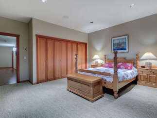 This charming bedroom boasts a cozy carpet, complemented by a wooden four-poster bed and matching nightstands.
