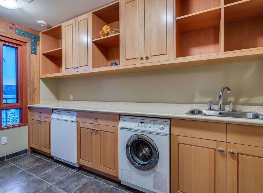 This stunning laundry room boasts ample storage with built-in wooden cabinets and shelving, providing a functional and organized space.