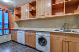 This stunning laundry room boasts ample storage with built-in wooden cabinets and shelving, providing a functional and organized space.