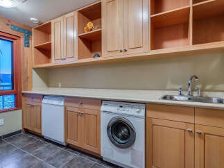 This stunning laundry room boasts ample storage with built-in wooden cabinets and shelving, providing a functional and organized space.