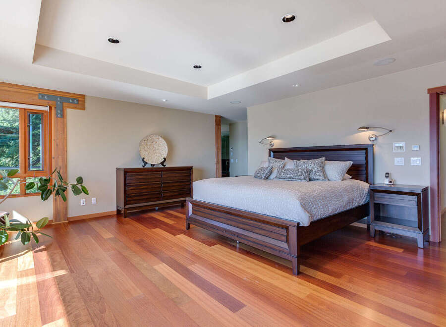 This luxurious bedroom boasts a stunning hardwood floor, large windows offering abundant natural light, and a spacious layout.