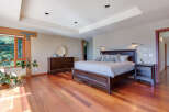 This luxurious bedroom boasts a stunning hardwood floor, large windows offering abundant natural light, and a spacious layout.