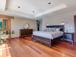 This luxurious bedroom boasts a stunning hardwood floor, large windows offering abundant natural light, and a spacious layout.