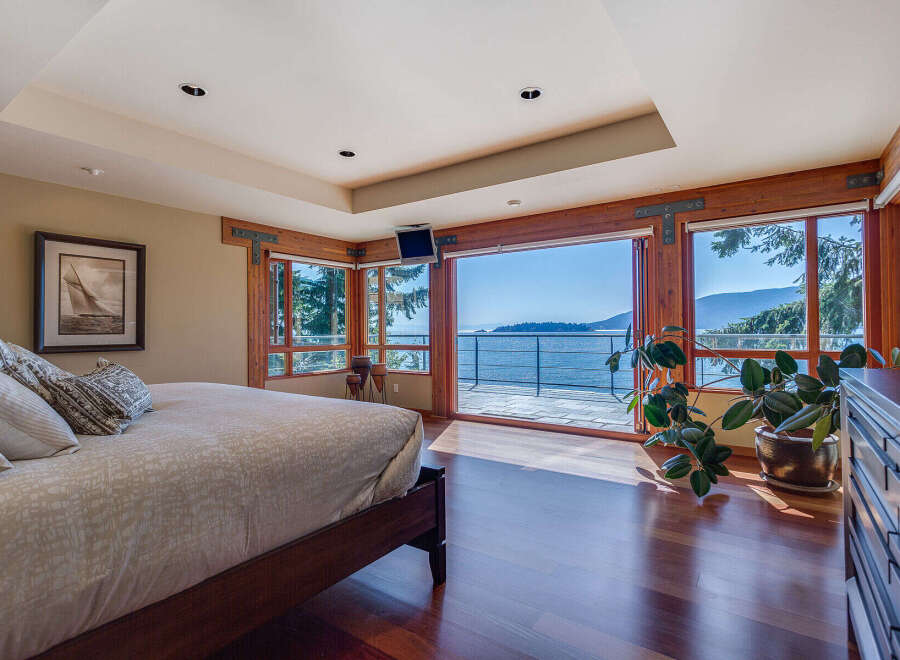 This luxurious bedroom boasts breathtaking ocean views from its expansive windows and private balcony.
