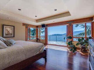 This luxurious bedroom boasts breathtaking ocean views from its expansive windows and private balcony.