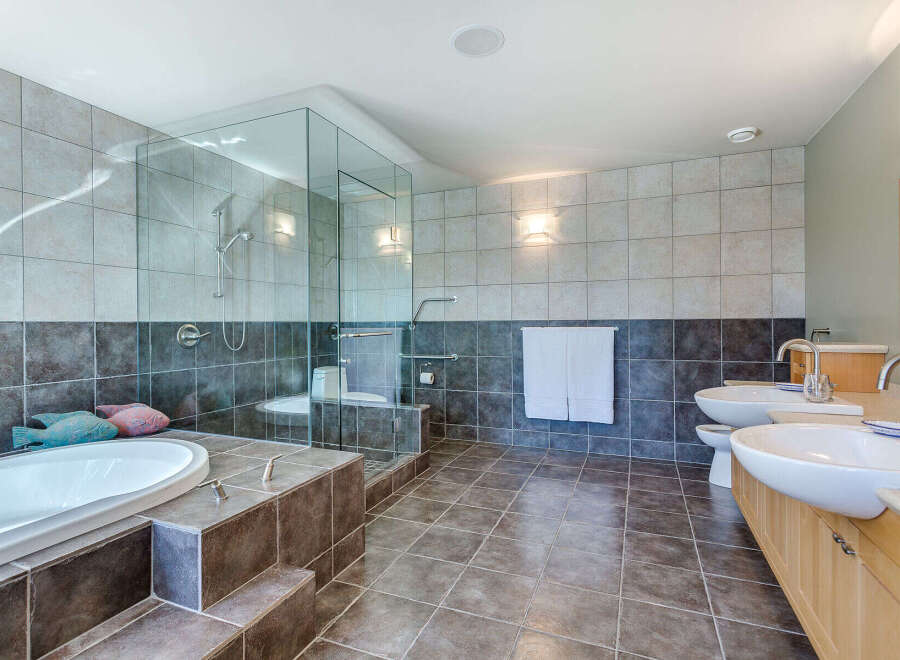 This luxurious bathroom boasts a spacious glass-enclosed shower, a deep soaking tub, and dual vanities with ample counter space.