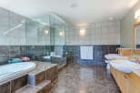 This luxurious bathroom boasts a spacious glass-enclosed shower, a deep soaking tub, and dual vanities with ample counter space.