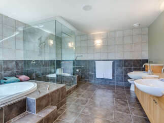 This luxurious bathroom boasts a spacious glass-enclosed shower, a deep soaking tub, and dual vanities with ample counter space.