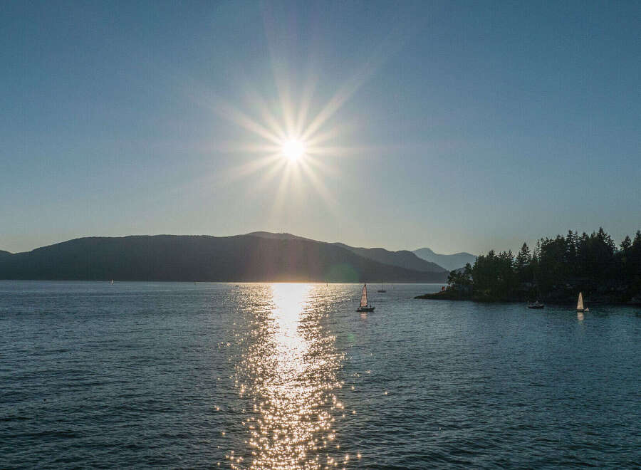 Spectacular sunset view over the calm waters, with sailboats gently gliding across the glistening surface.