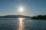 Spectacular sunset view over the calm waters, with sailboats gently gliding across the glistening surface.