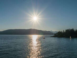 Spectacular sunset view over the calm waters, with sailboats gently gliding across the glistening surface.