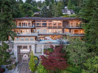 This stunning waterfront mansion boasts a multi-level design with expansive windows offering breathtaking views, a private infinity pool, and a built-in boat lift for convenient water access.