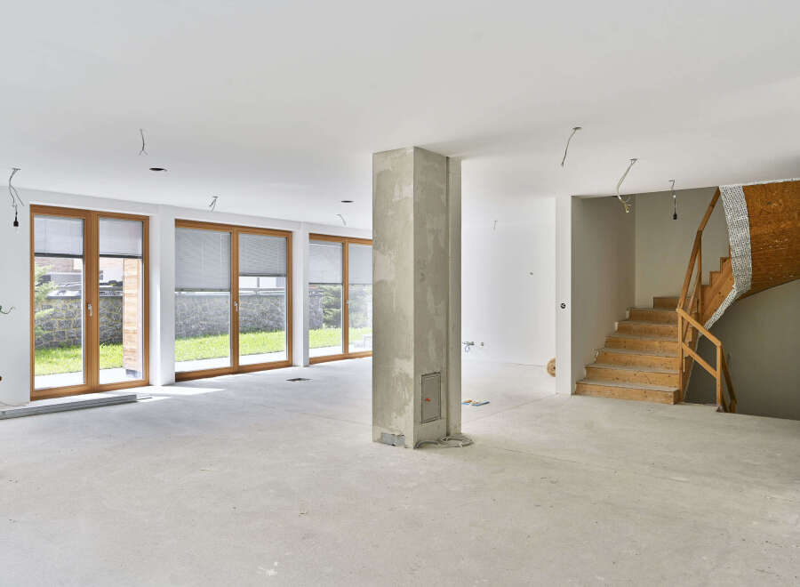 This stunning property boasts a spacious open-plan living area with large windows offering ample natural light and views of the lush green surroundings.