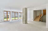 This stunning property boasts a spacious open-plan living area with large windows offering ample natural light and views of the lush green surroundings.