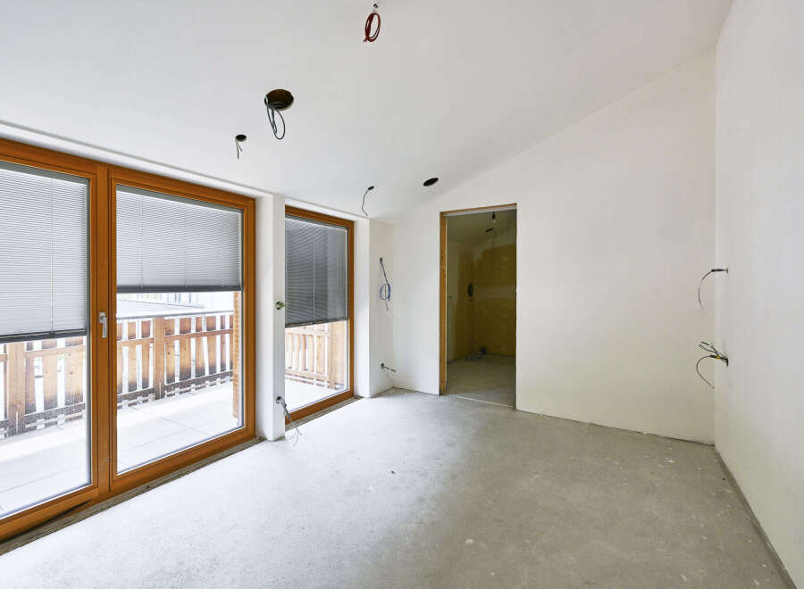 This property features an open-plan living space with large windows offering ample natural light and views of an outdoor patio.