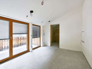 This property features an open-plan living space with large windows offering ample natural light and views of an outdoor patio.