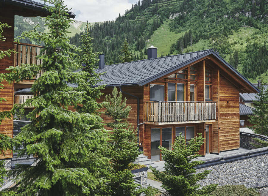 Nestled in a mountainside, this stunning wooden chalet boasts a spacious balcony with wooden railings, offering breathtaking views of the surrounding landscape.