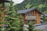Nestled in a mountainside, this stunning wooden chalet boasts a spacious balcony with wooden railings, offering breathtaking views of the surrounding landscape.