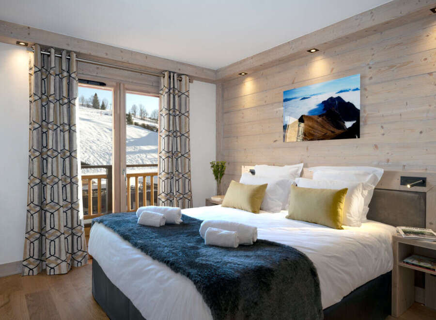 This stunning bedroom boasts a cozy and luxurious atmosphere, complete with a plush bed, soft furs, and elegant curtains.