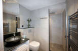 Modern bathroom with a sleek black sink, white toilet, and a walk-in shower.