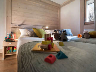 Cozy bedroom with twin beds, featuring a rustic wooden wall and soft textiles.