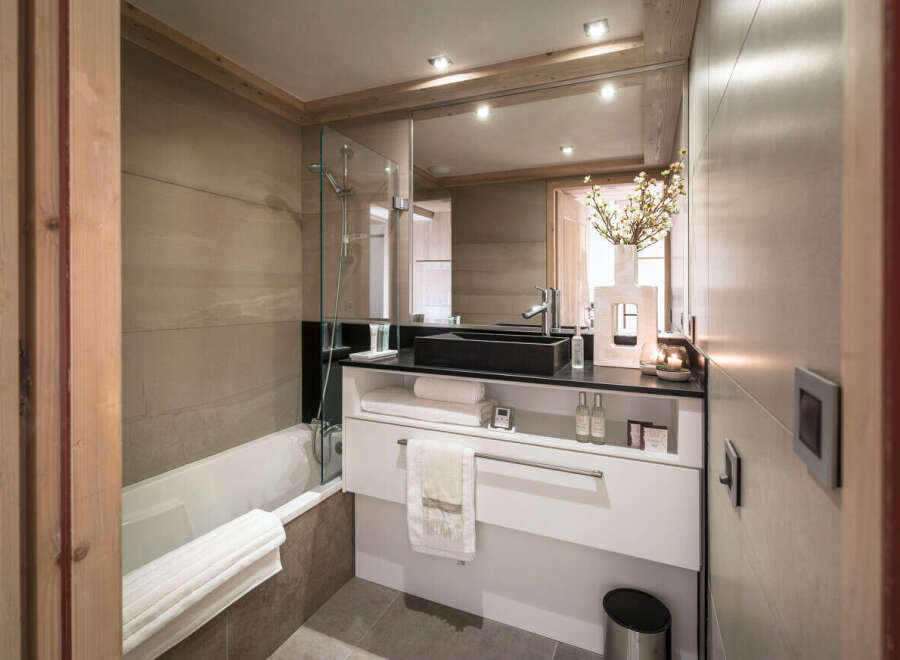 This luxurious bathroom boasts a modern design with sleek black countertops and a spacious bathtub.