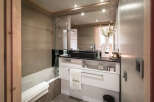 This luxurious bathroom boasts a modern design with sleek black countertops and a spacious bathtub.
