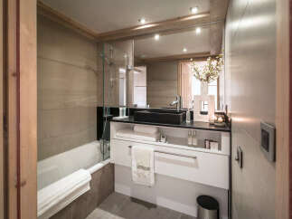 This luxurious bathroom boasts a modern design with sleek black countertops and a spacious bathtub.
