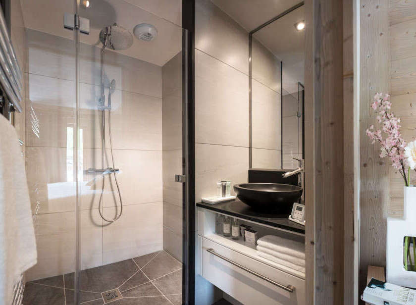 This modern bathroom boasts a spacious shower with glass enclosure, a sleek vanity with ample storage, and stylish fixtures.