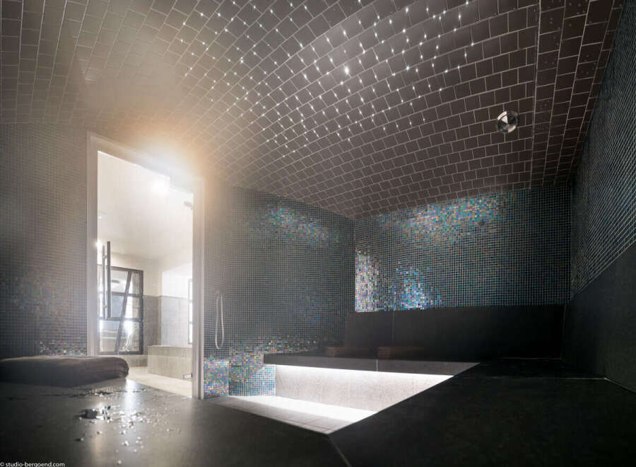 This luxurious spa features a stunning steam room with iridescent mosaic tiles and a vaulted ceiling adorned with fiber optic lights.