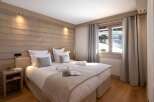 Cozy bedroom with wooden walls and a comfortable bed, perfect for a relaxing stay.