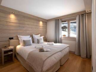 Cozy bedroom with wooden walls and a comfortable bed, perfect for a relaxing stay.
