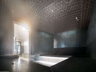 This luxurious spa features a stunning steam room with iridescent mosaic tiles and a vaulted ceiling adorned with fiber optic lights.