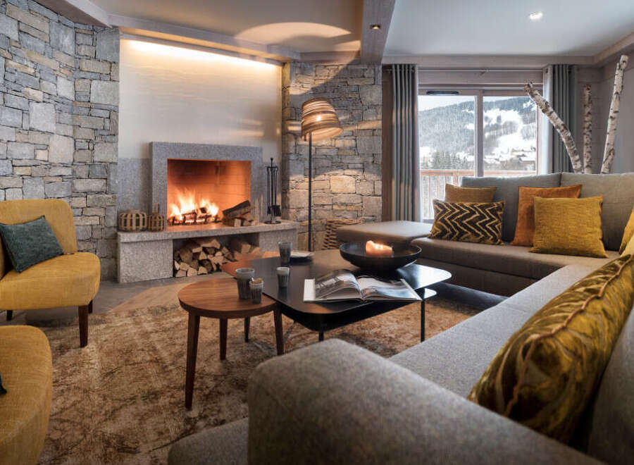 This stunning chalet boasts a cozy living room with a large stone fireplace, creating a warm and inviting atmosphere.