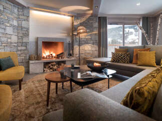 This stunning chalet boasts a cozy living room with a large stone fireplace, creating a warm and inviting atmosphere.