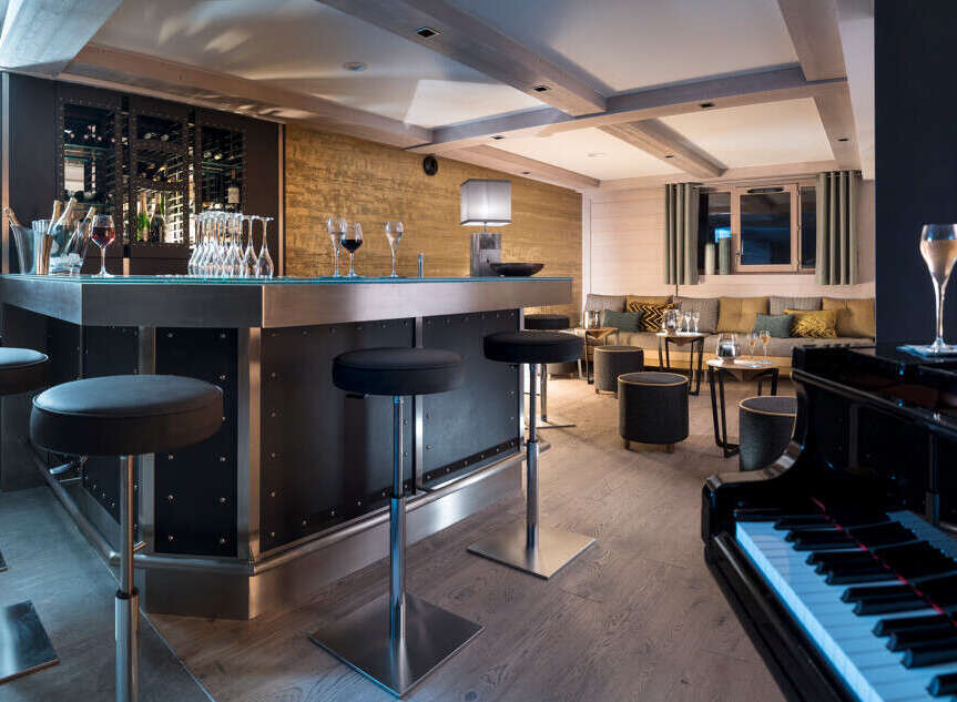 This luxurious chalet boasts a stylish bar area complete with a sleek metal countertop, comfortable bar stools, and a sophisticated wine rack.