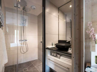 This modern bathroom boasts a spacious shower with glass enclosure, a sleek vanity with ample storage, and stylish fixtures.
