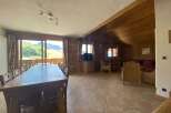 This stunning chalet boasts a spacious open-plan living area with a large dining table perfect for family gatherings, and comfortable seating arrangements for relaxation.