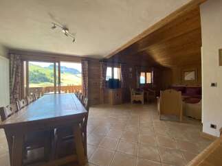 This stunning chalet boasts a spacious open-plan living area with a large dining table perfect for family gatherings, and comfortable seating arrangements for relaxation.