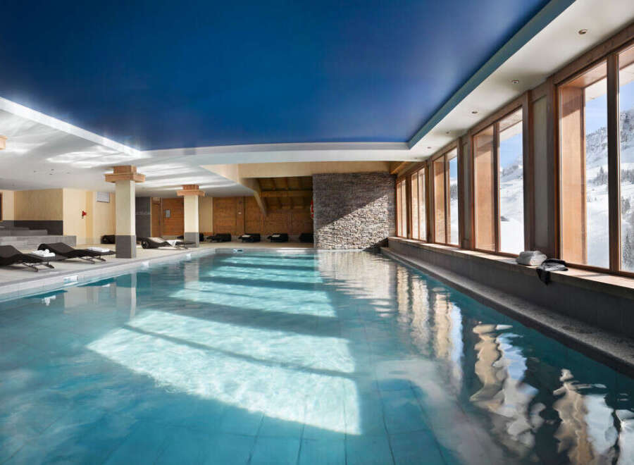 Indulge in a luxurious indoor pool experience, surrounded by floor-to-ceiling windows offering breathtaking mountain views.
